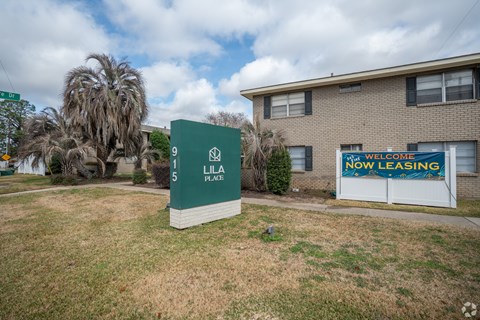 A sign in front of a building that says "Welcome Now Leasing".