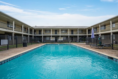 A swimming pool in front of a building with balconies.