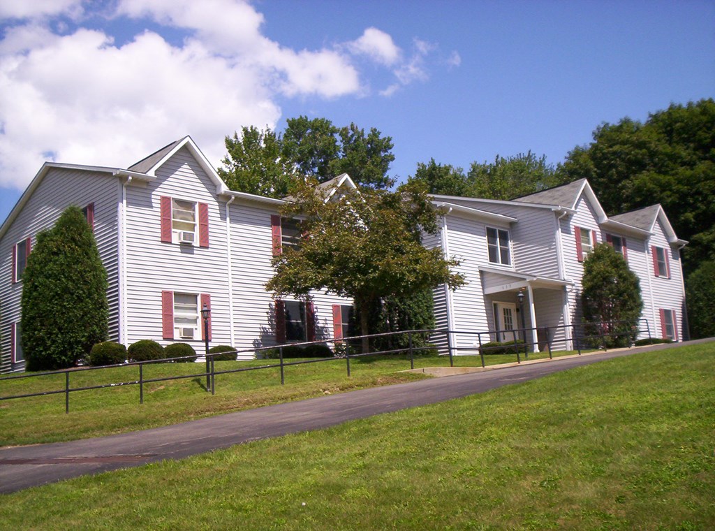 a white house with red shutters and a grassy yard