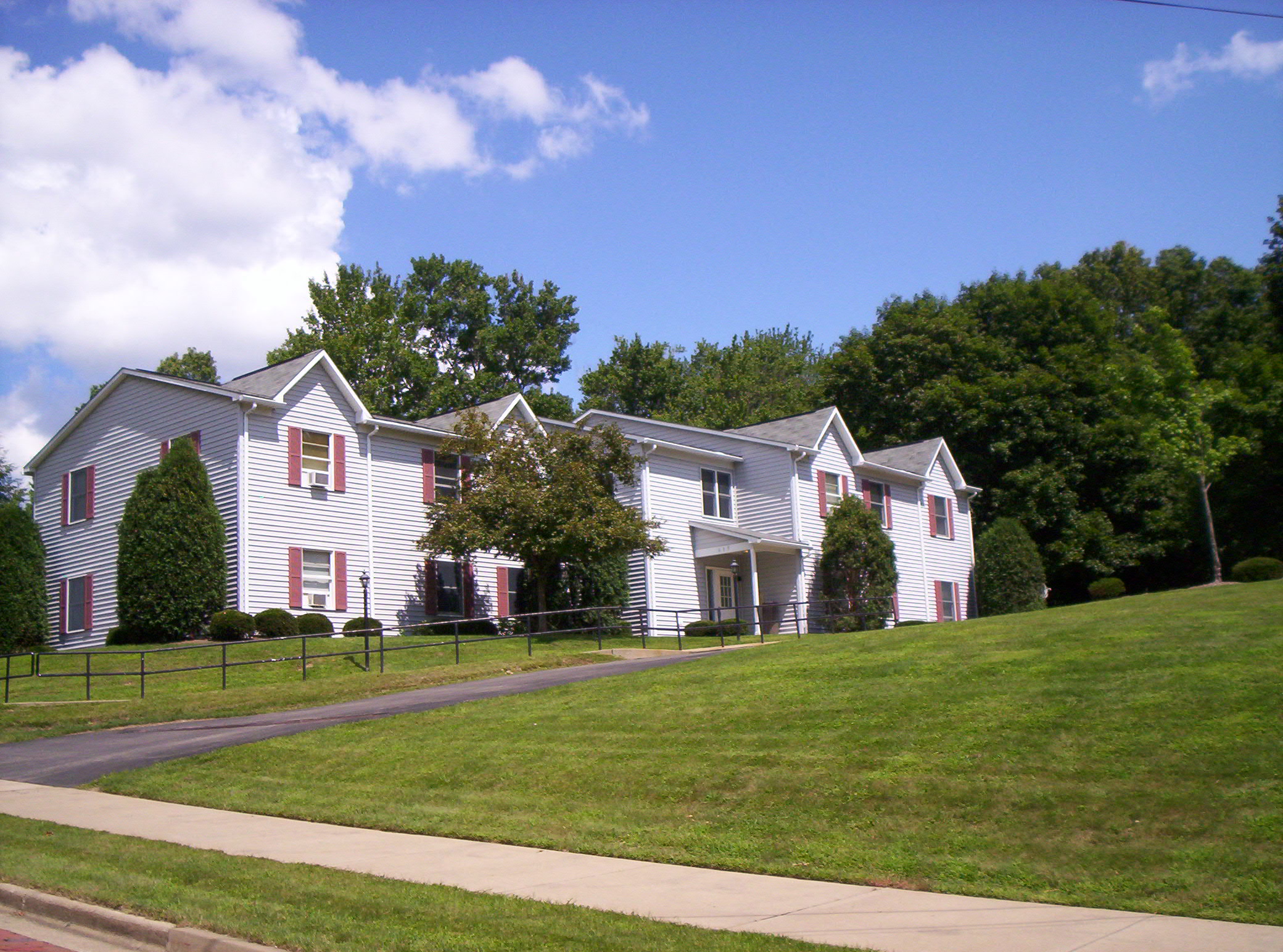 a white house with red shuttered windows on a hill