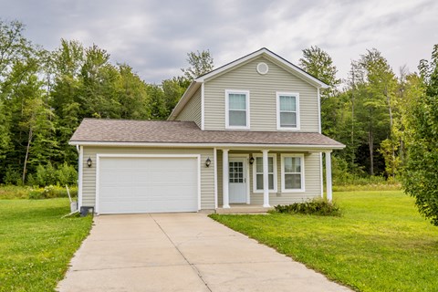 a small gray house with a white garage door