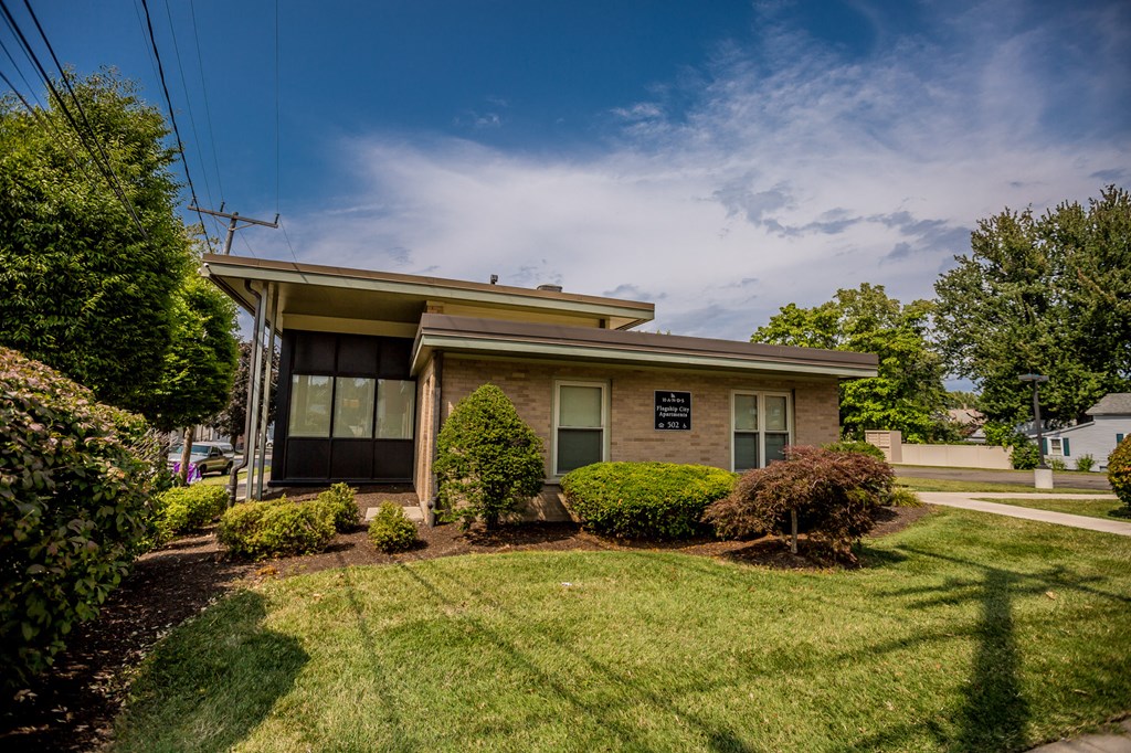 a small brick house with a lawn and bushes