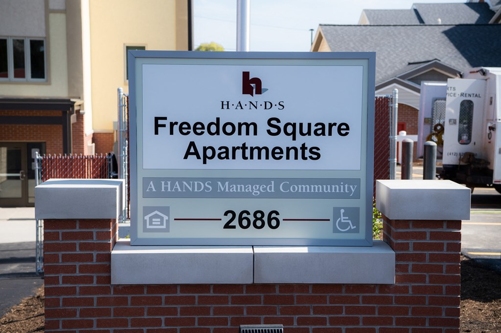 a sign for freedom square apartments in front of a house