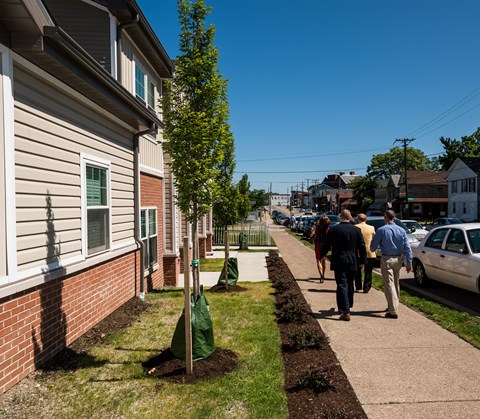 people walking down the sidewalk in front of a house