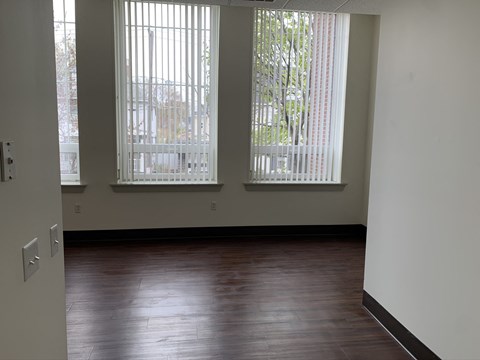 an empty living room with wood floors and large windows