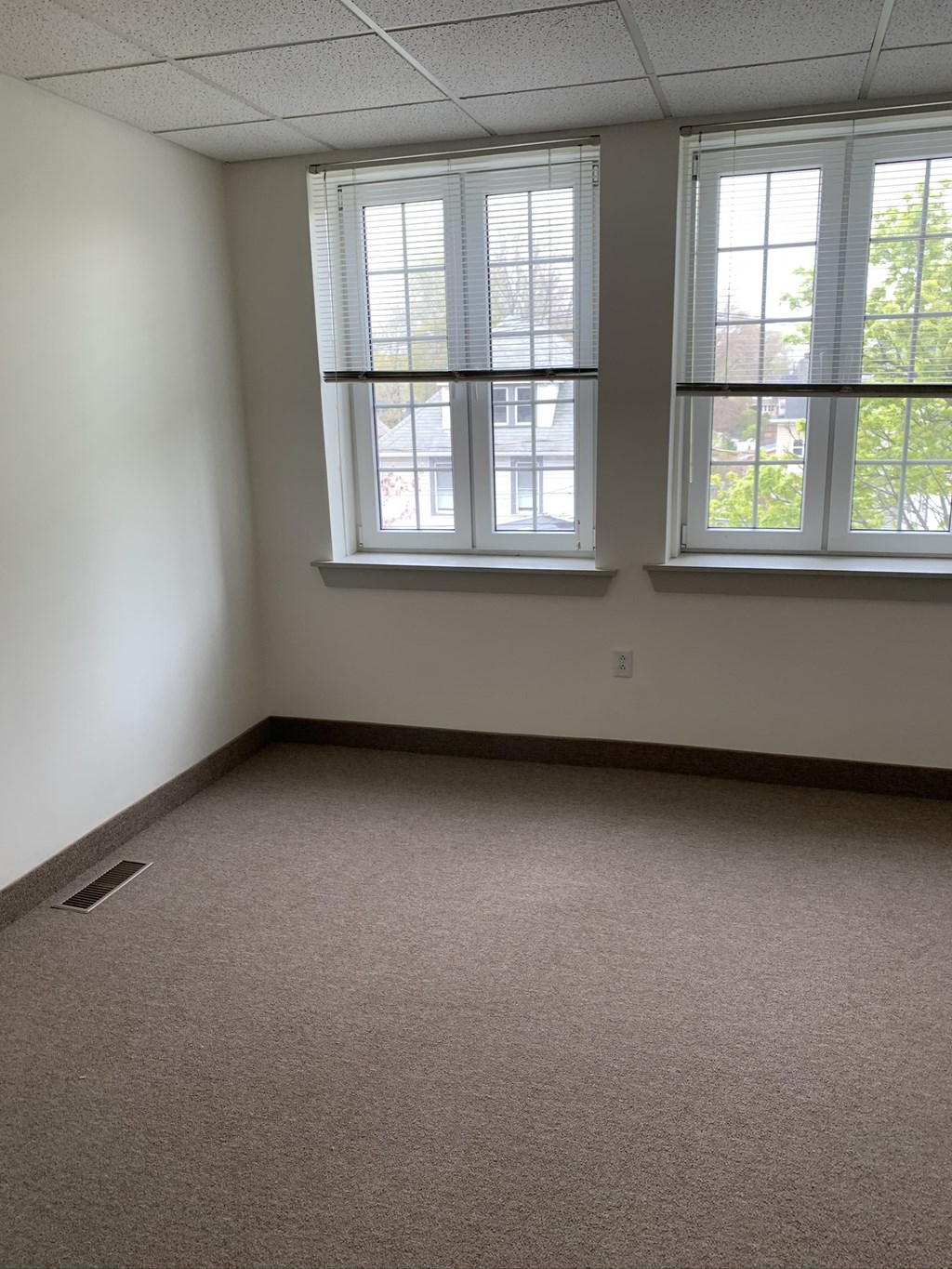 an empty room with three windows and a carpeted floor