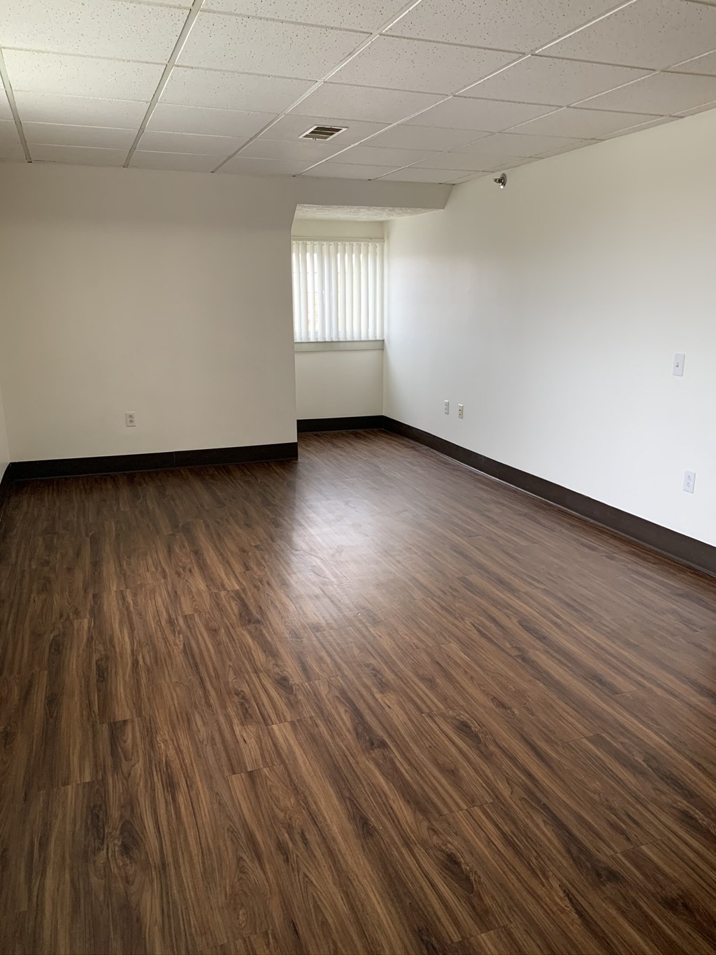 an empty room with wooden floors and a window