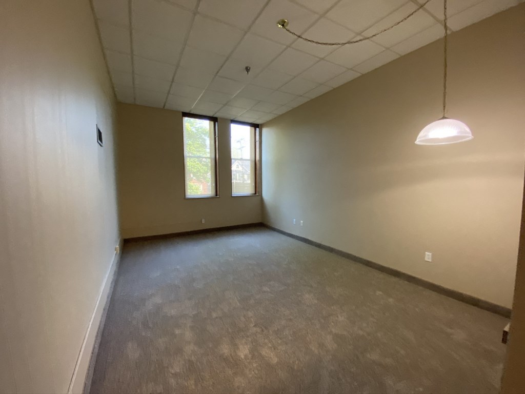 an empty room with a lamp hanging from the ceiling and windows