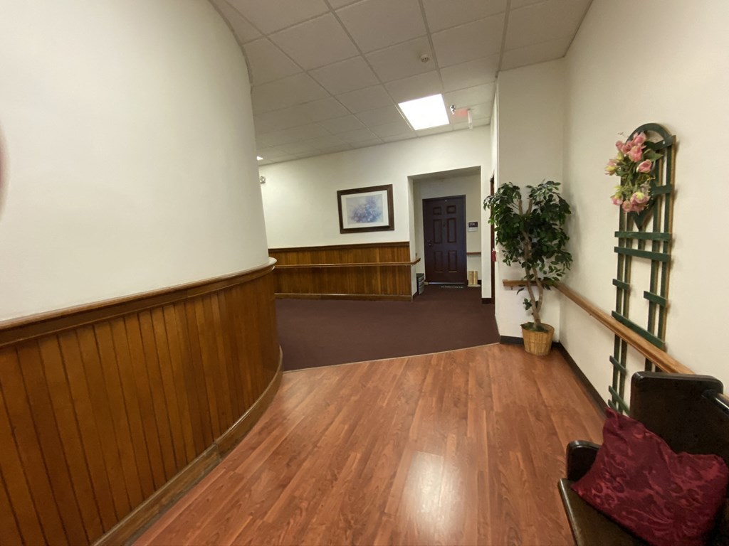 a view of a hall with wood floors and a door