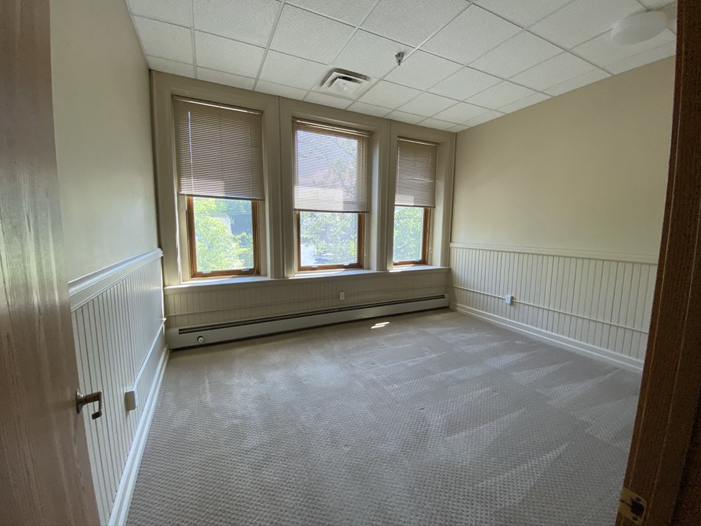 an empty room with three windows and a radiator