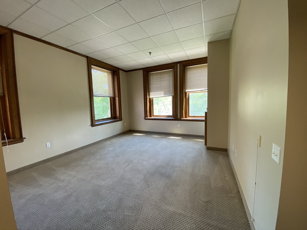 an empty room with three windows and a carpeted floor
