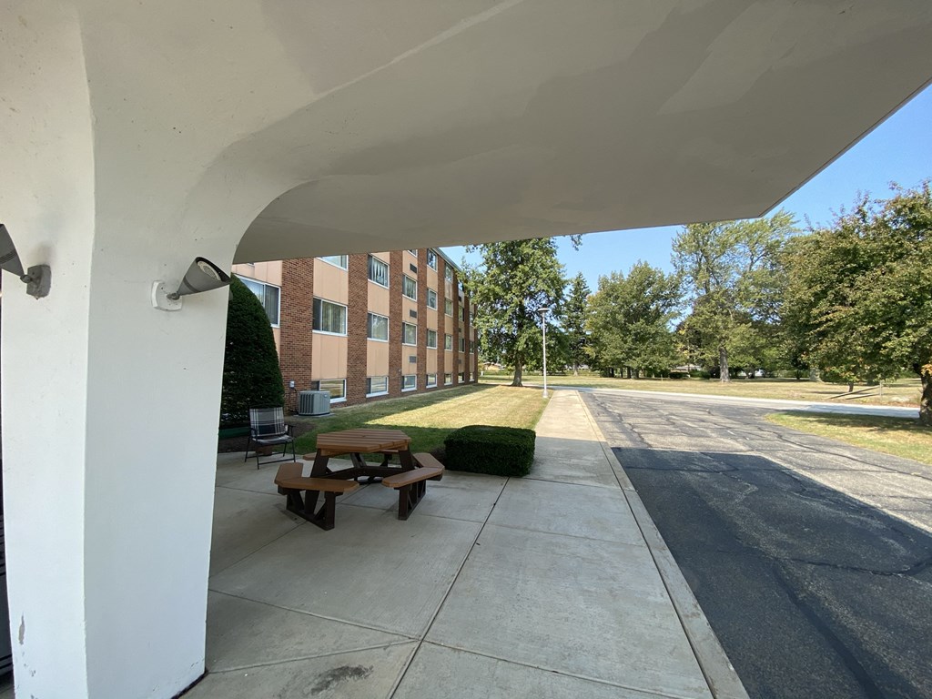 a covered porch with a picnic table in front of a building