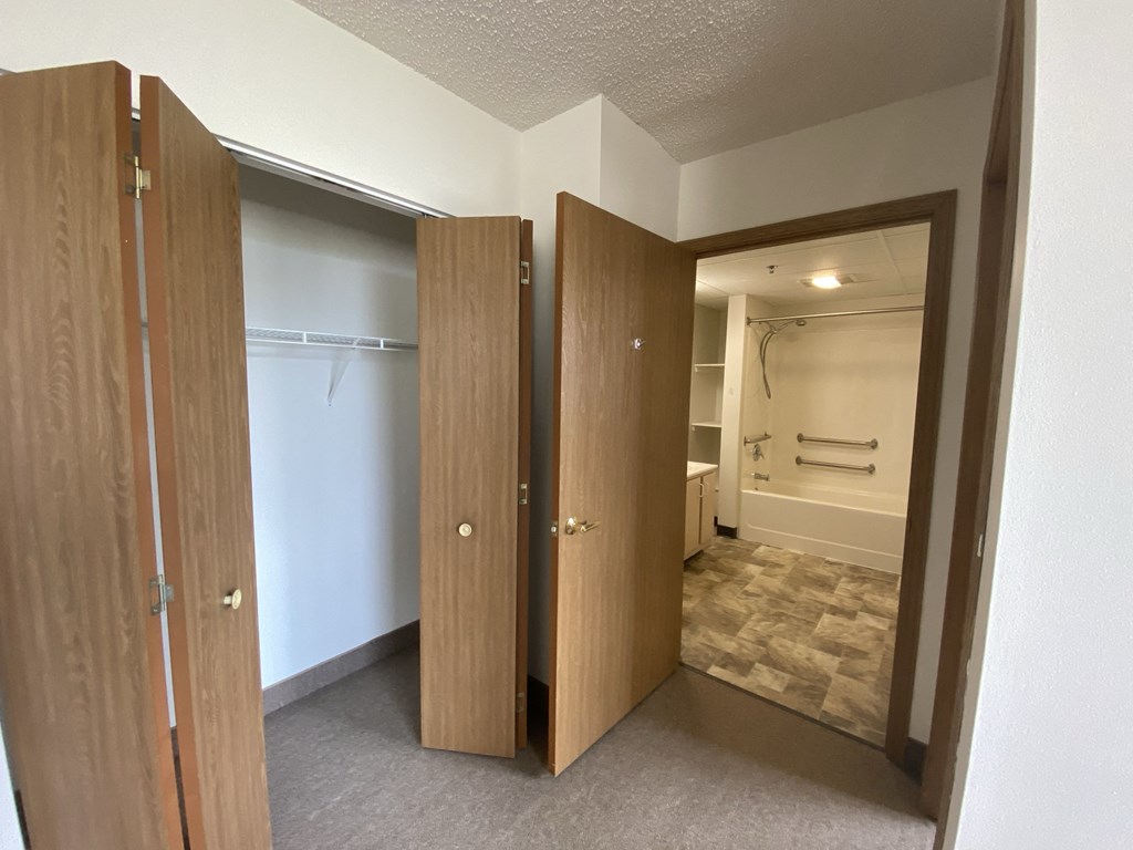 a bathroom with two doors and a closet and a shower