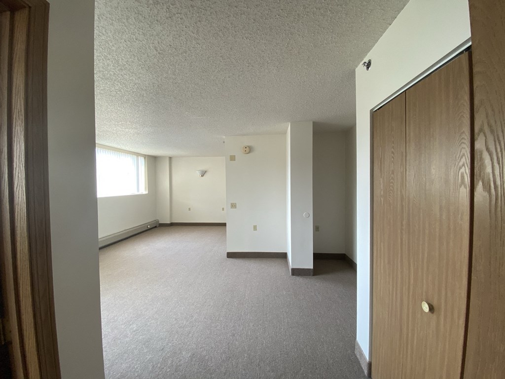 an empty living room with a closet and a window