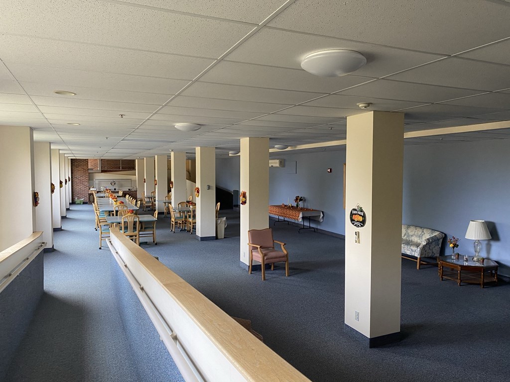 a large room with tables and chairs and a hallway with columns