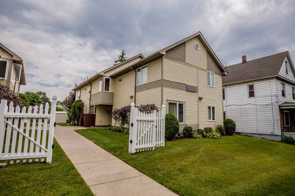 a house with a white picket fence and a sidewalk