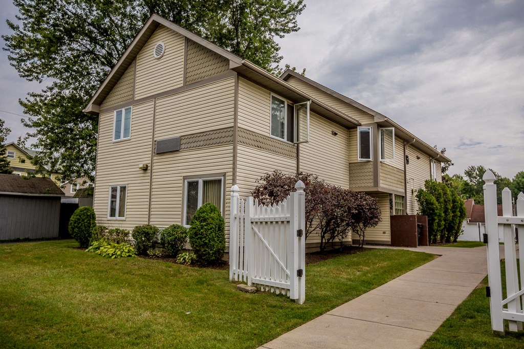 a yellow house with a white fence and a sidewalk