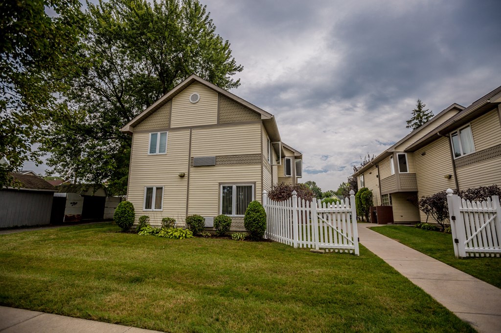 a house with a white picket fence in front of a green yard