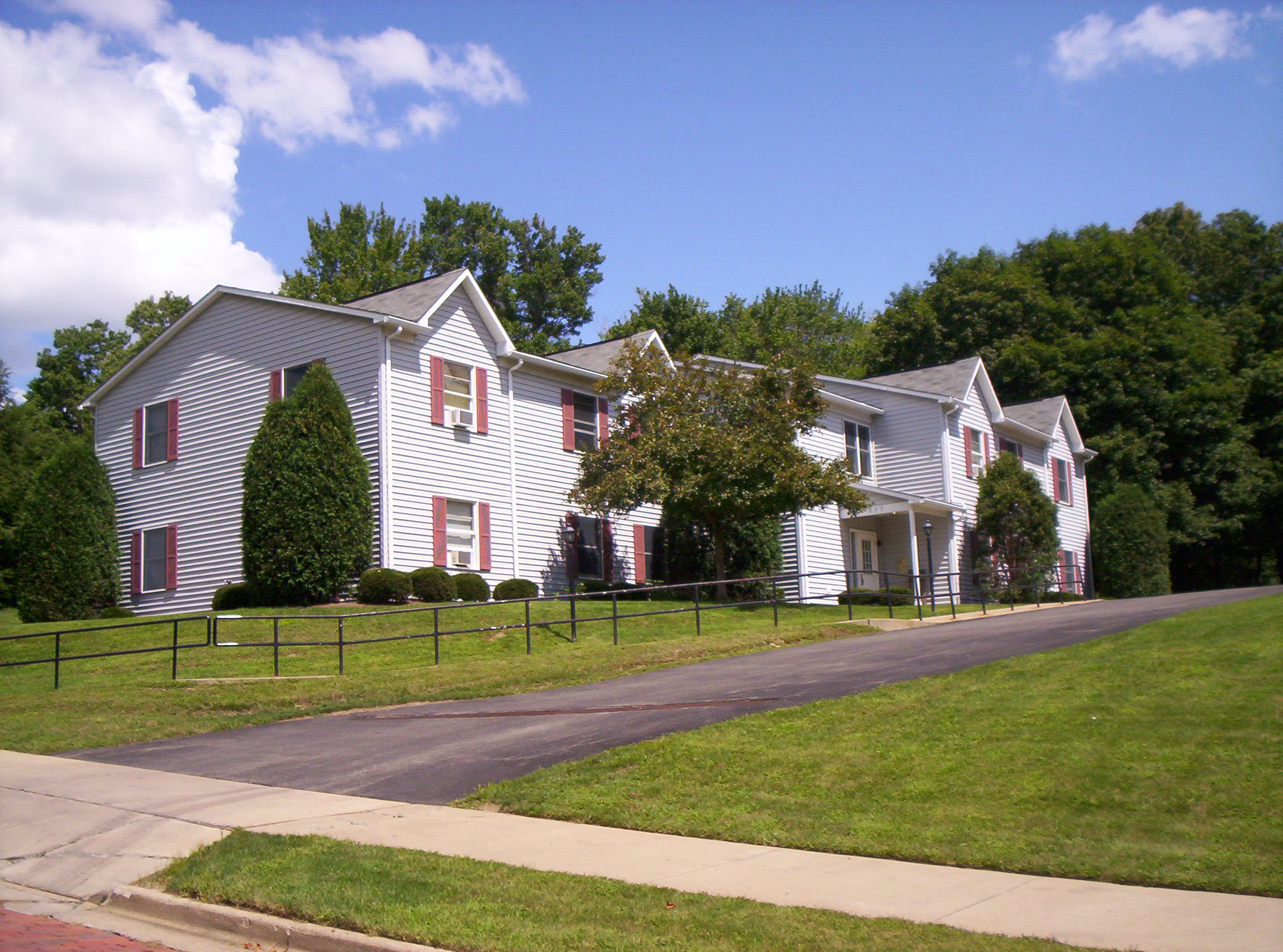 a white house with red shuttered windows on the side of a street