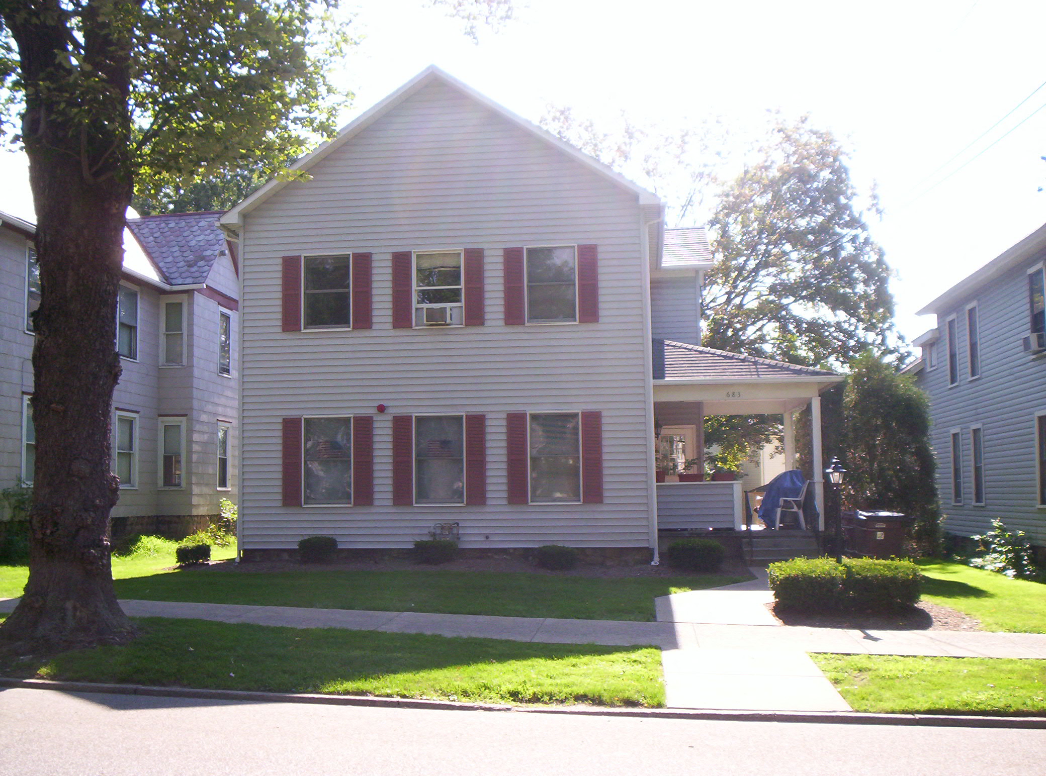 a white house with red shutters and a sidewalk in front of it