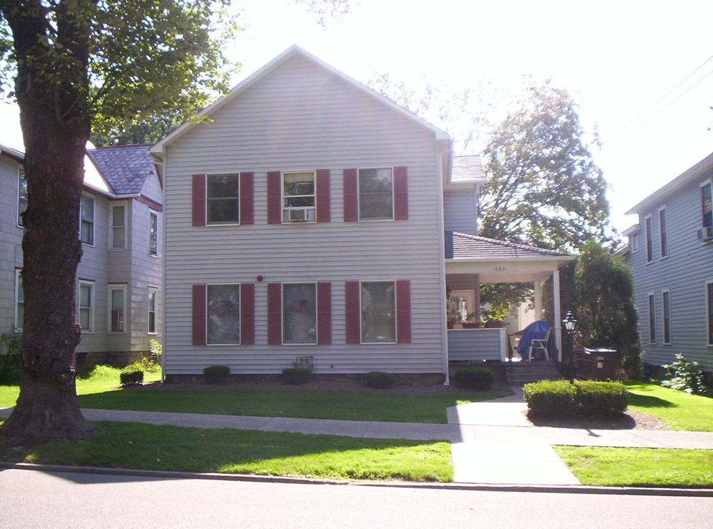 a white house with red shutters and a sidewalk in front of it