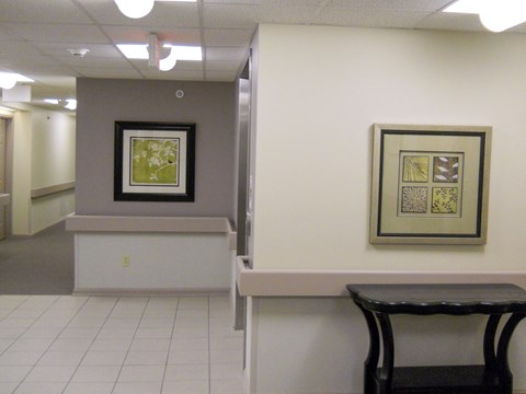 a hallway with a table and a chair and paintings on the wall