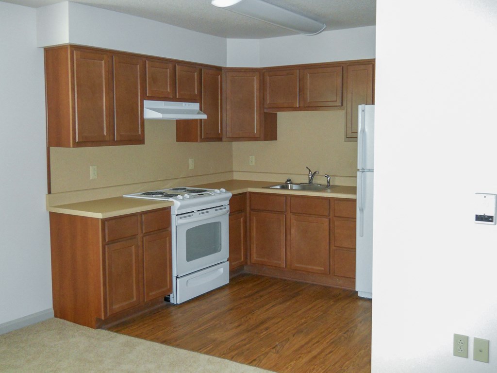 an empty kitchen with wooden cabinets and a white stove and refrigerator