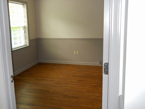 an empty room with wooden floors and a window