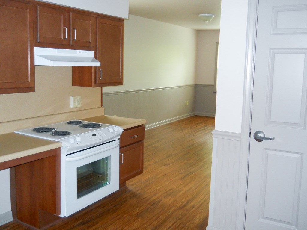 an empty kitchen with wood flooring and a white stove