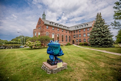 a statue of a frog in front of a brick building