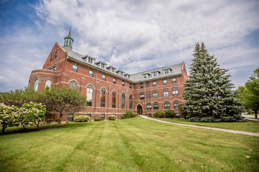 a large brick building with a lawn and a tree