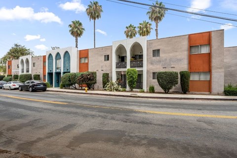 A street view of a building with palm trees in the background.