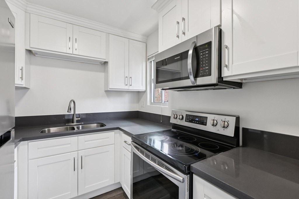 A modern kitchen with white cabinets and a black countertop.