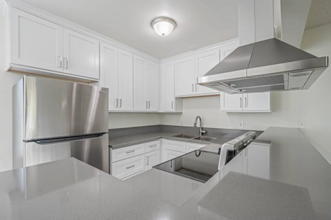 A modern kitchen with a stainless steel refrigerator and a range hood.