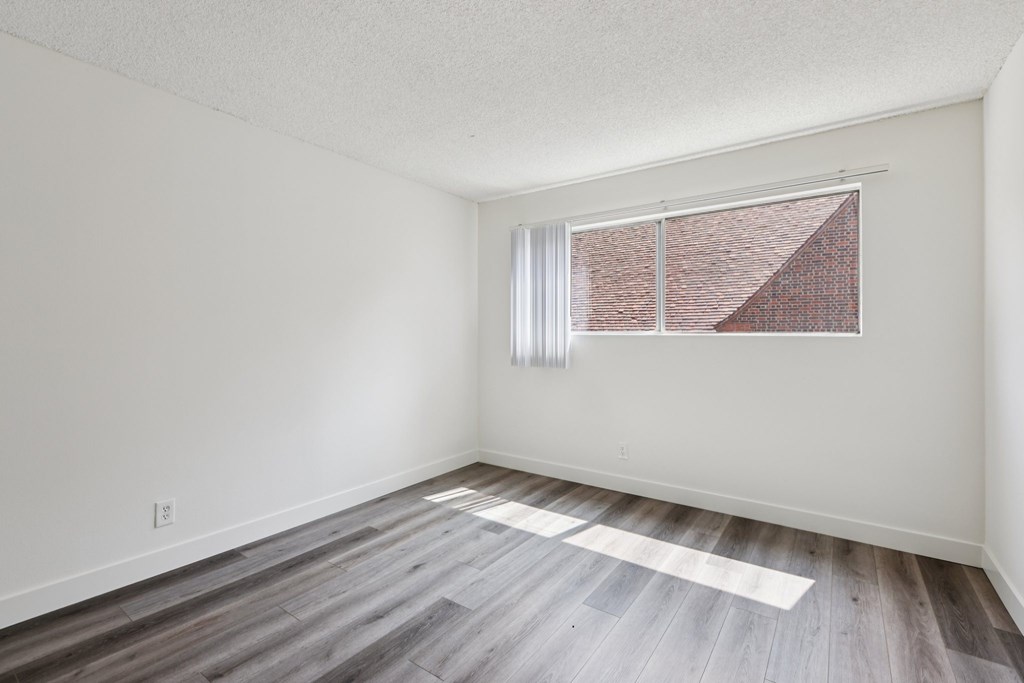 A room with a window and wooden flooring.