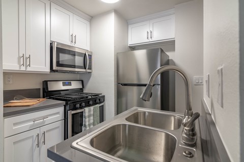 A modern kitchen with a stainless steel sink and refrigerator.