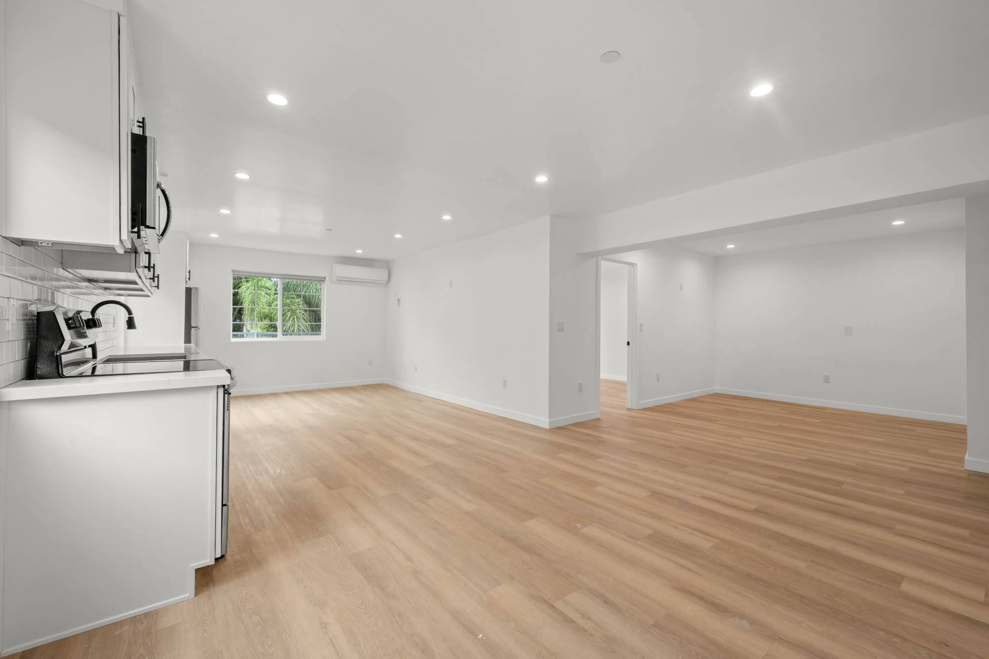 A kitchen with white cabinets and a wooden floor.