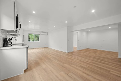 A kitchen with white cabinets and a wooden floor.