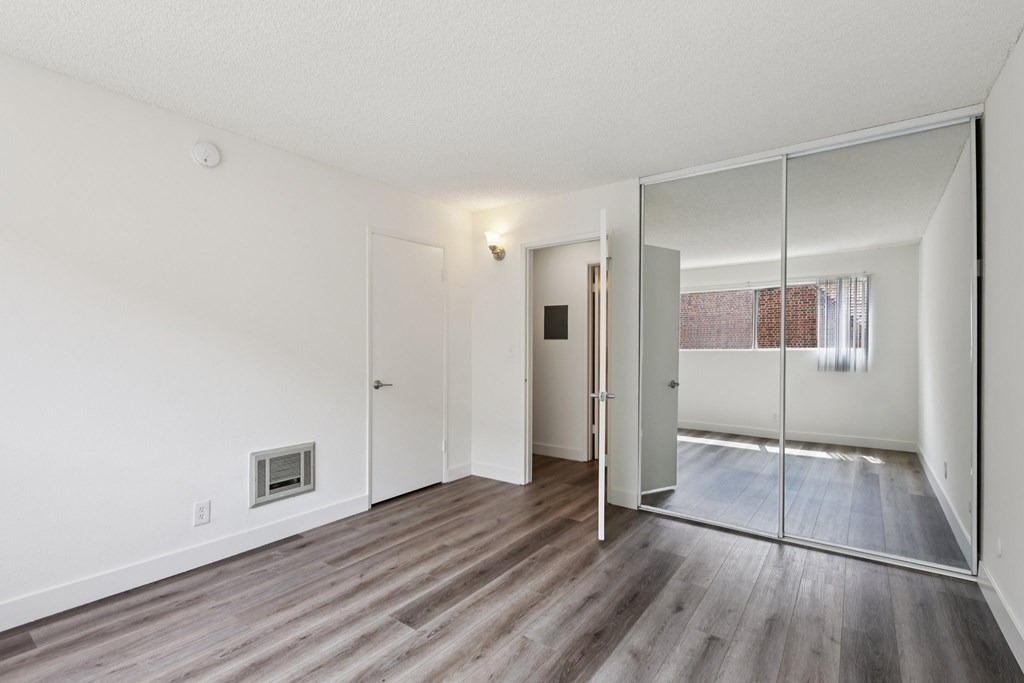 A room with a white wall and a mirror on the door.