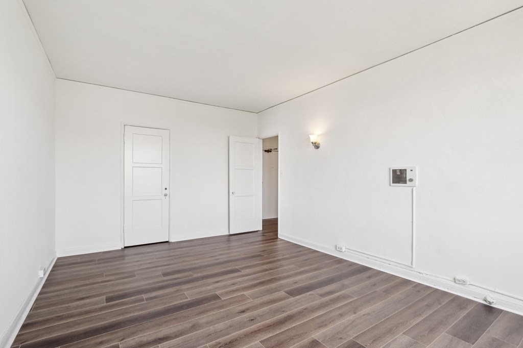 A room with wooden flooring and white walls.