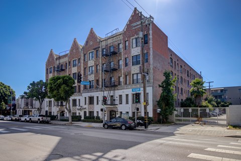 A large brick building with a white section in the middle is situated on a street corner.