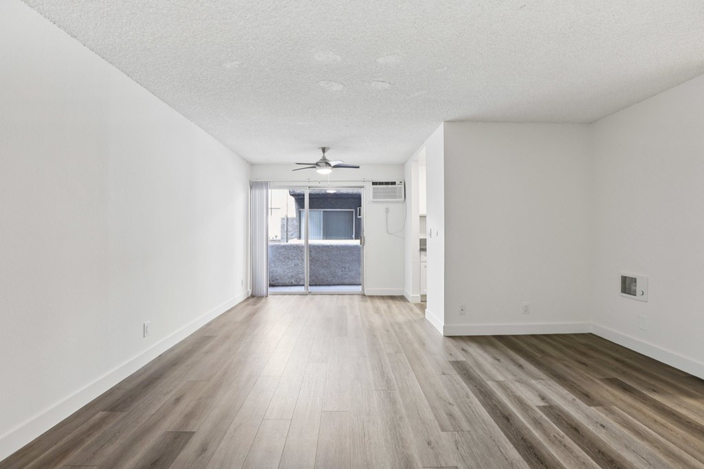 A room with a ceiling fan and sliding glass doors.