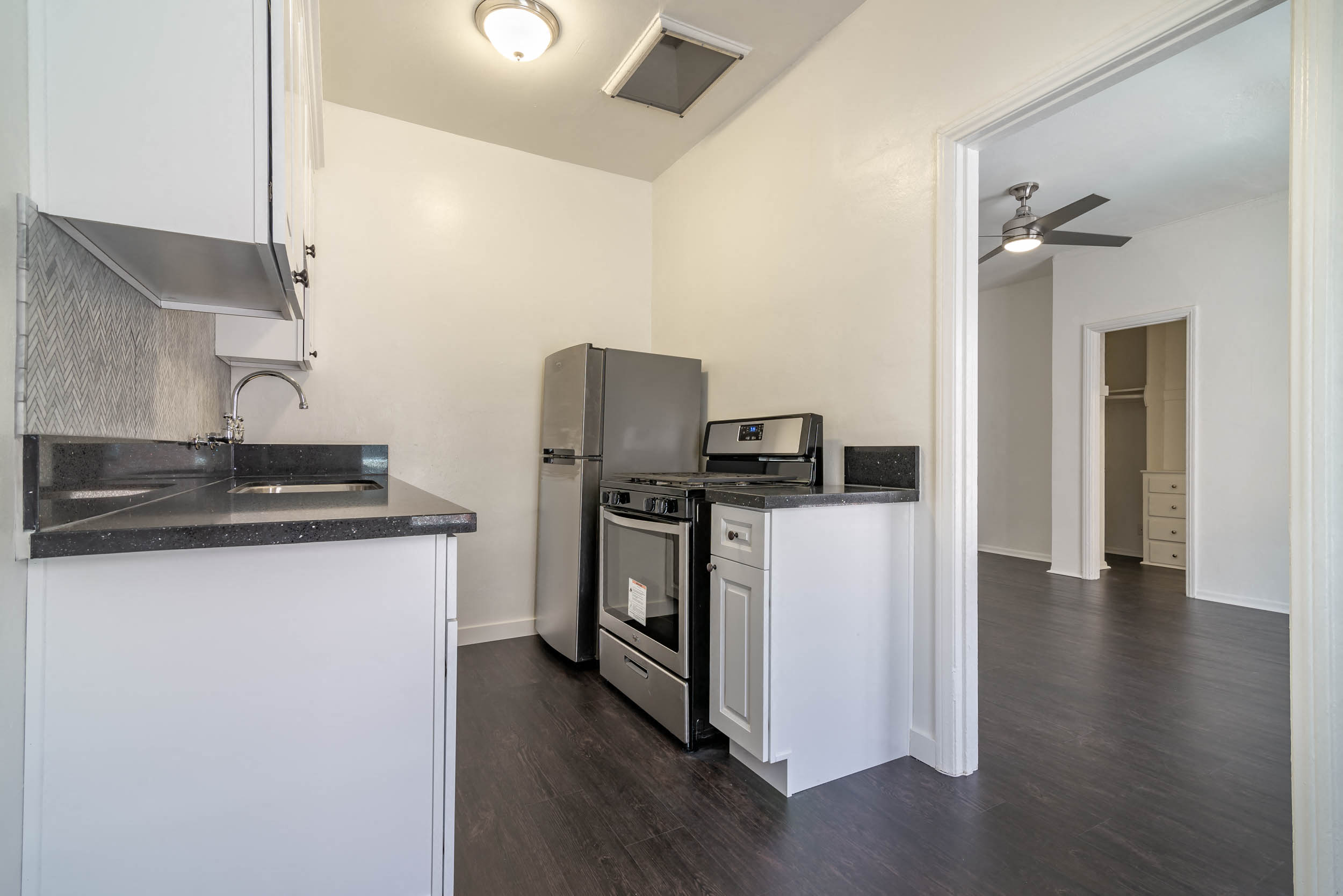 A kitchen with white cabinets and a black countertop.