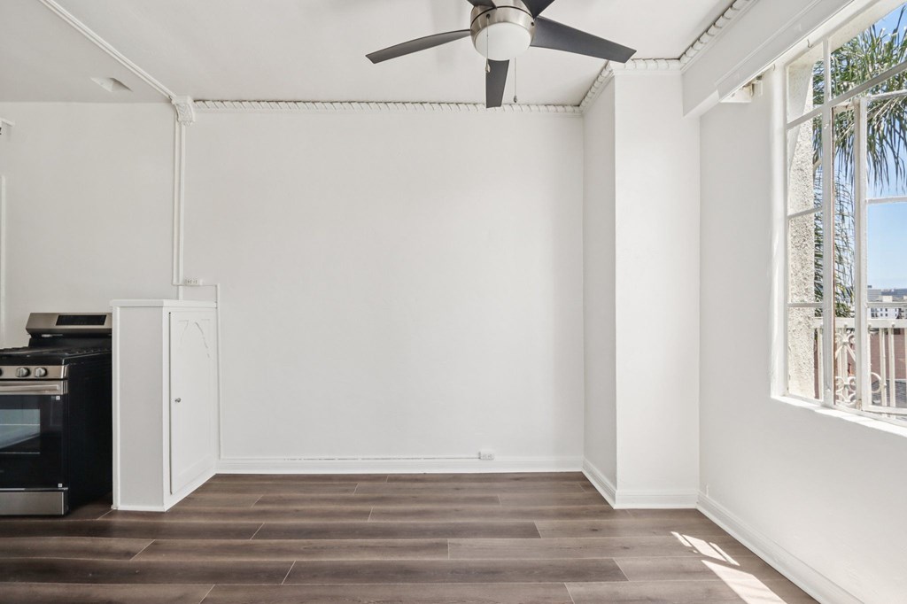 A room with a ceiling fan and a window overlooking a balcony.