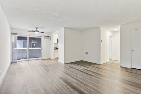 A spacious room with wooden flooring and a ceiling fan.