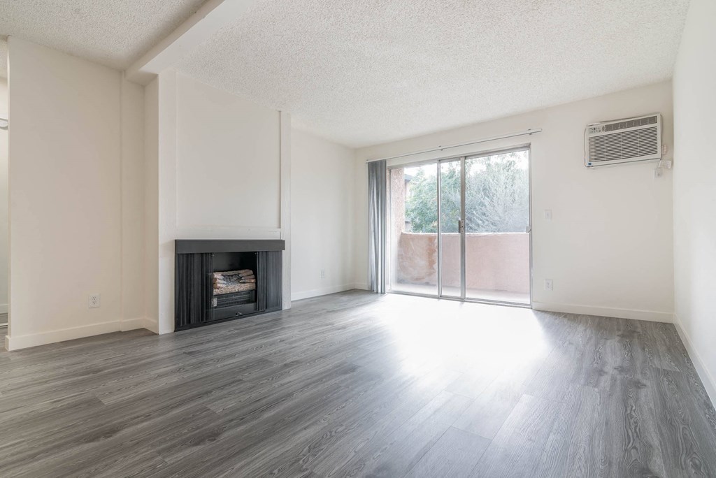 an empty living room with a fireplace and a sliding glass door