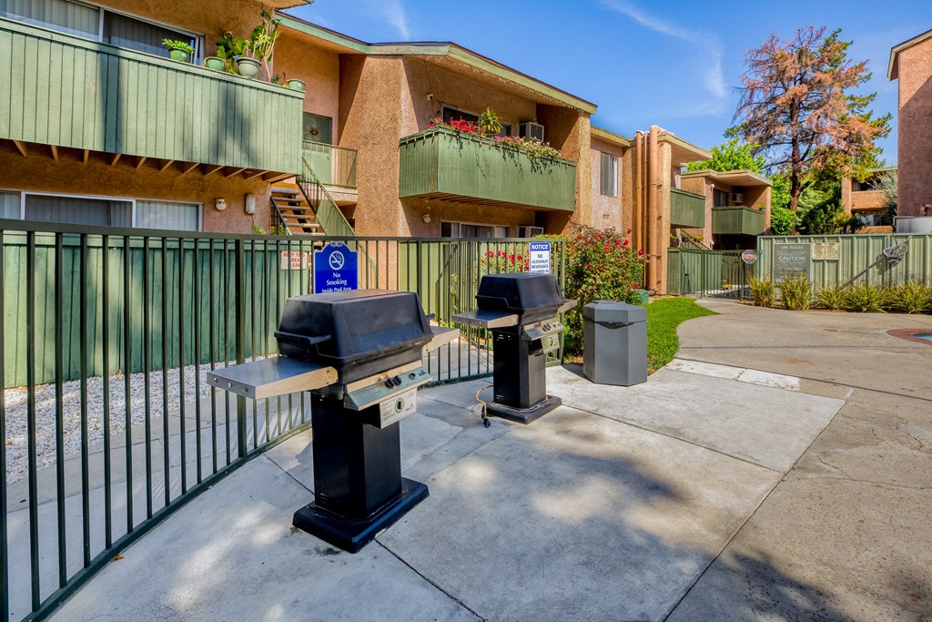 two parking meters in front of an apartment building with a fence