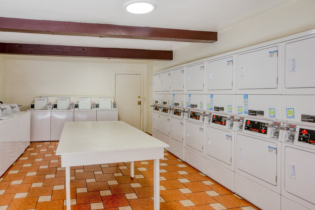 a laundry room with a white table and a row of washing machines
