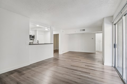 A spacious room with wooden flooring and white walls.