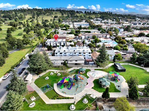 A playground with a slide and a red pin on a building.